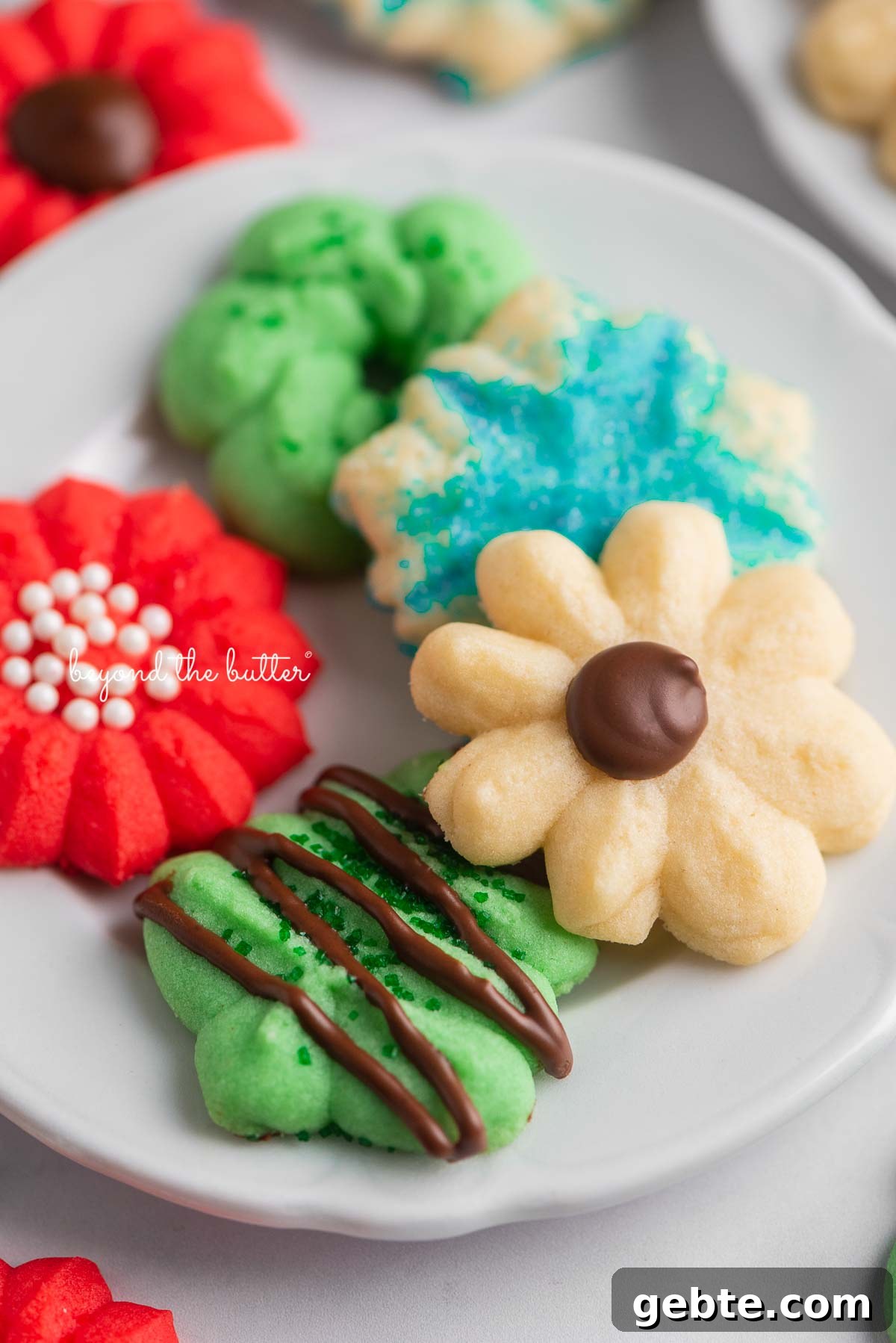Tiny dessert plates with classic spritz cookies on a white marble background | © Beyond the Butter®