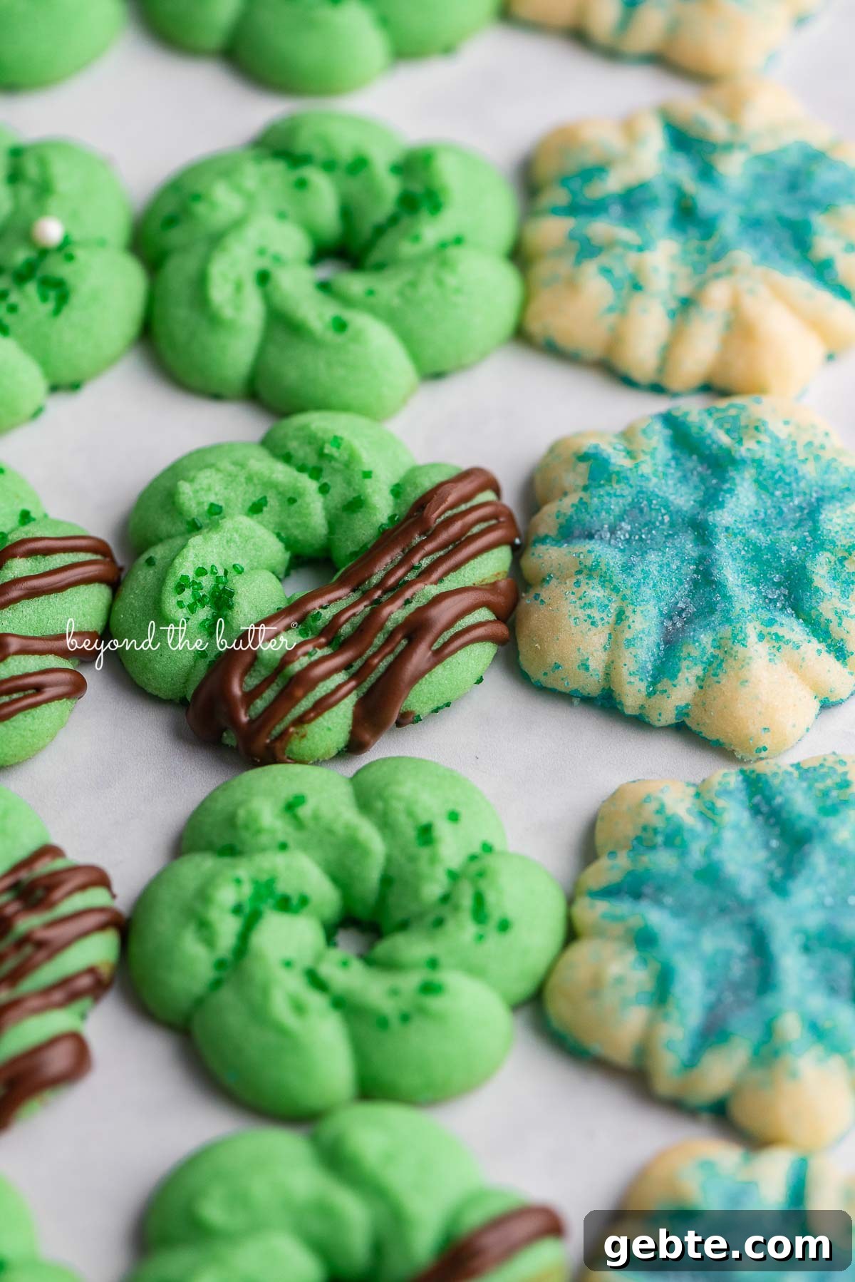 Decorated classic buttery spritz cookies lined up on a white marbled background | © Beyond theButter®