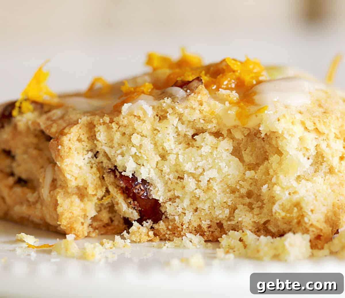 Close-up image of bitten cranberry orange scone on whitish background.