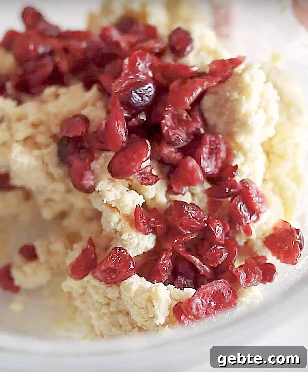 Dried cranberries added to scone dough in a glass bowl. Close up image.