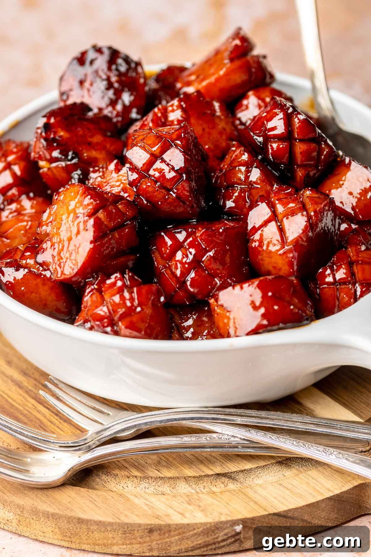 Sweet and Spicy Kielbasa Bites — 2-Ingredient Party Appetizer 2 A bowl full of kielbasa bites with cocktail forks next to it.