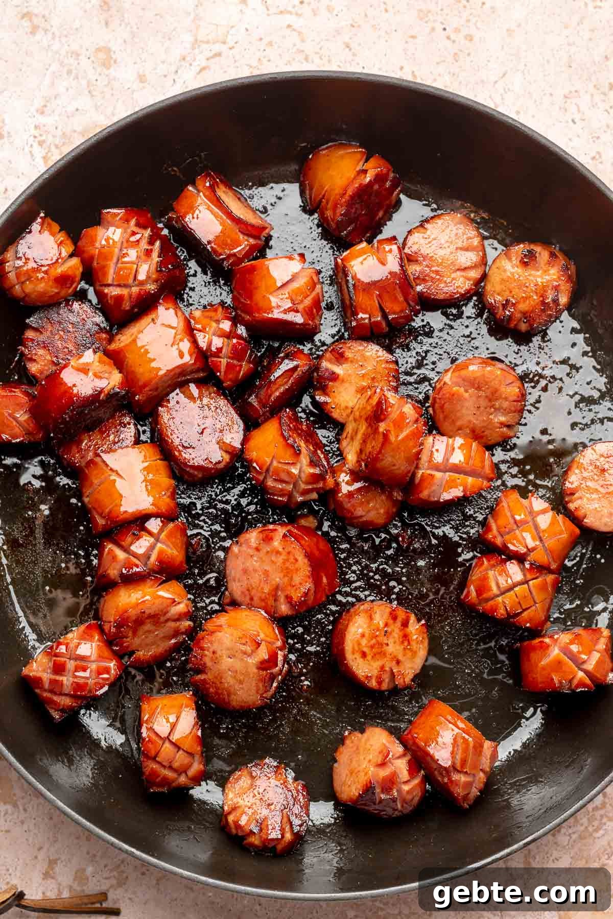 Sweet and Spicy Kielbasa Bites — 2-Ingredient Party Appetizer 5 Caramelized kielbasa in a frying pan.