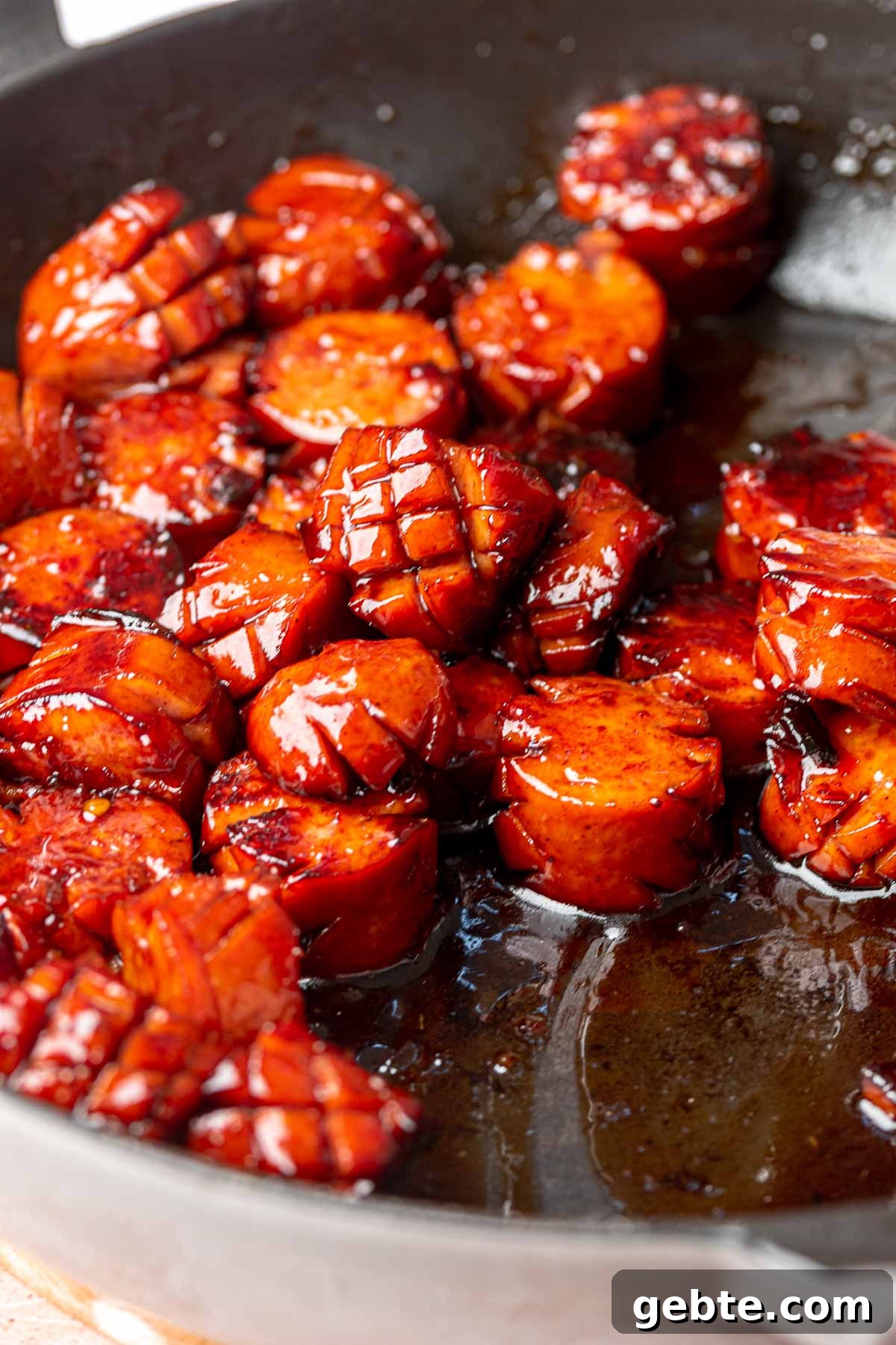 Sweet and Spicy Kielbasa Bites — 2-Ingredient Party Appetizer 6 Glazed kielbasa in a frying pan.