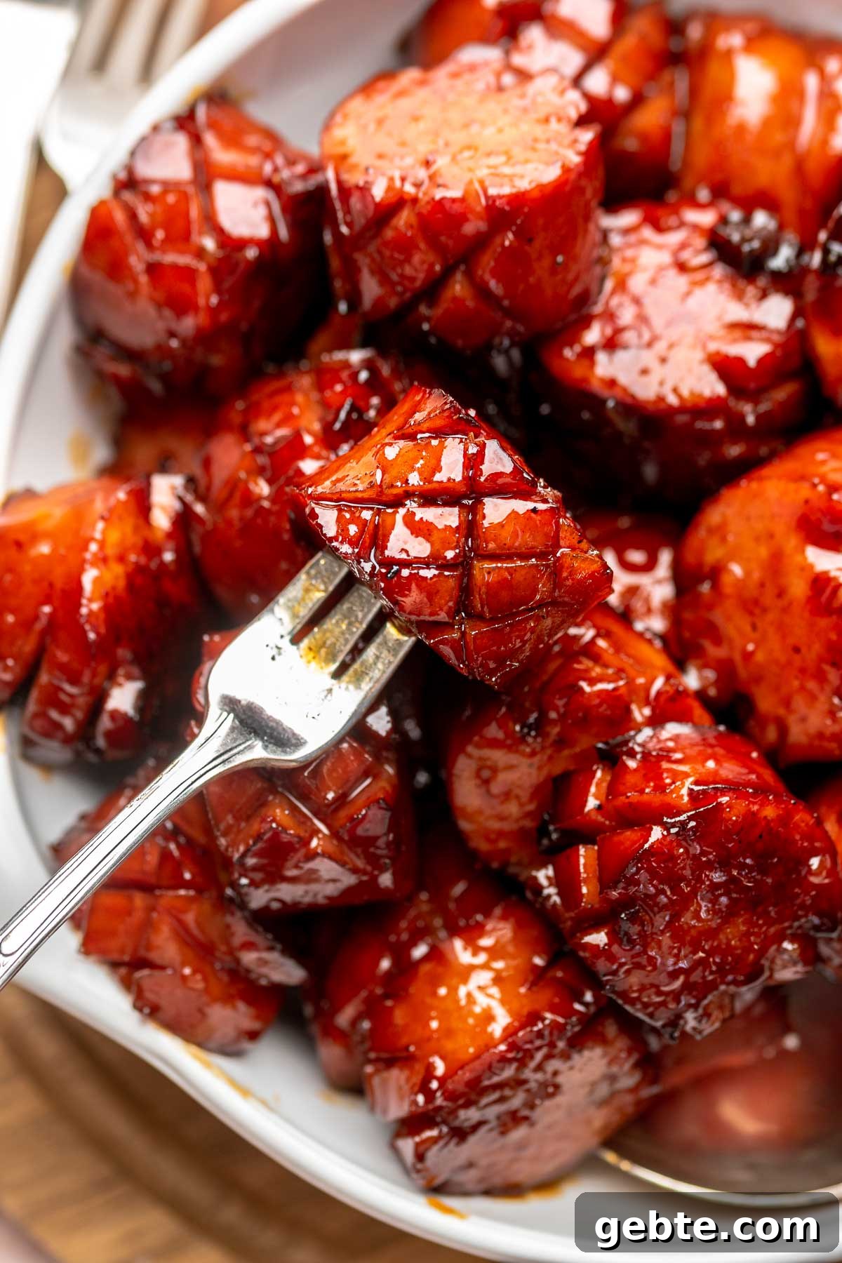 Sweet and Spicy Kielbasa Bites — 2-Ingredient Party Appetizer 7 A fork holds a chunk of kielbasa in a bowl of other pieces.