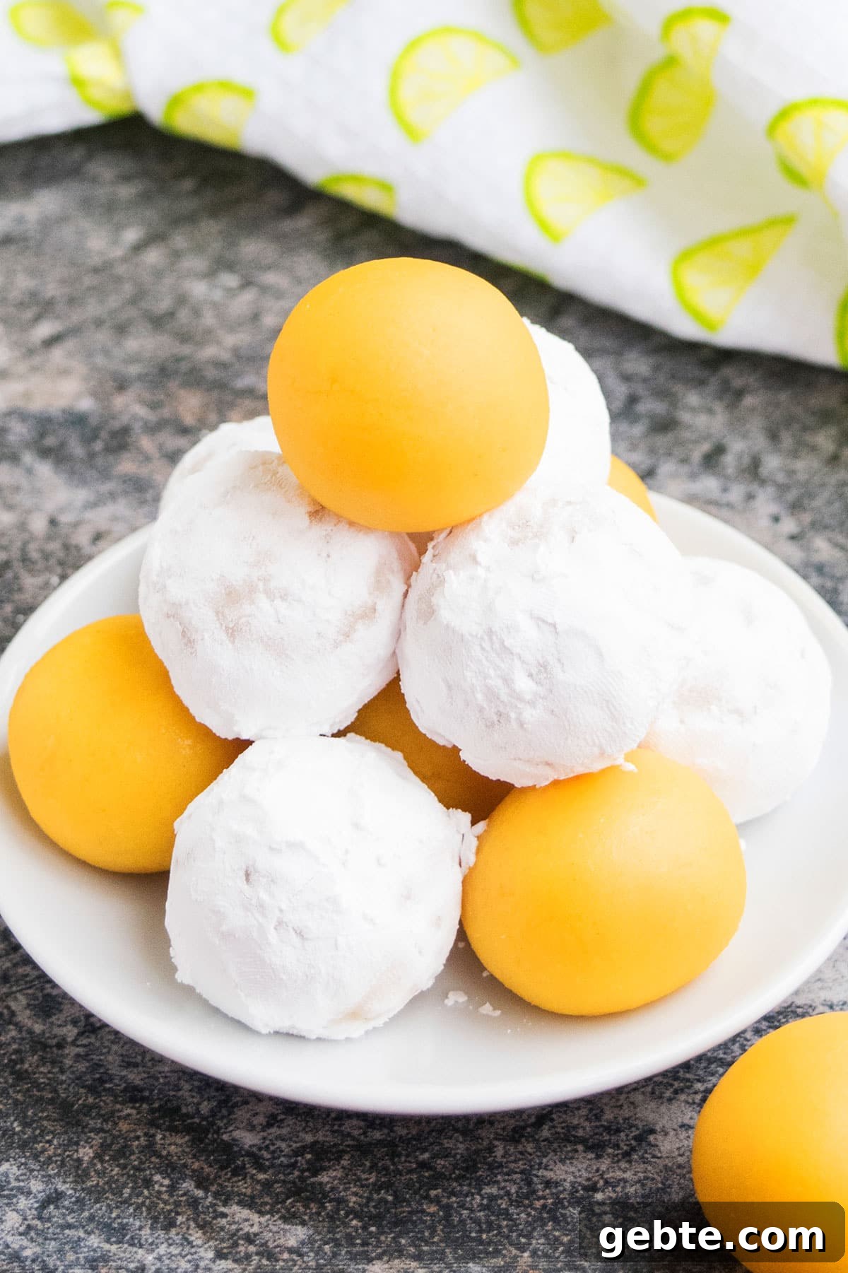 Lemon Cake Truffles: Zesty Bite-Sized Dessert Recipe 2 White dish with stack of no bake candy and some are covered in powdered sugar.