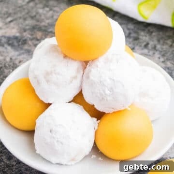 Lemon Cake Truffles: Zesty Bite-Sized Dessert Recipe 12 Tower of Lemon Cake Balls or Cake Truffles on white dish where Some are Coated in Powdered Sugar.