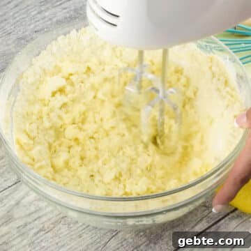 Lemon Cake Truffles: Zesty Bite-Sized Dessert Recipe 5 Ingredients being mixed together in glass bowl with hand held mixer.