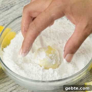 Lemon Cake Truffles: Zesty Bite-Sized Dessert Recipe 8 Balls being rolled in a bowl of powdered sugar.