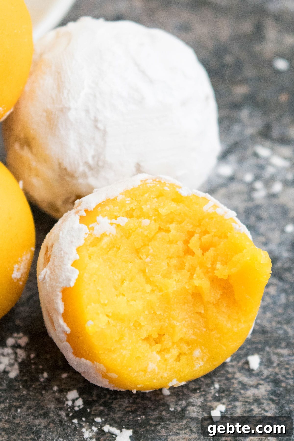 Lemon Cake Truffles: Zesty Bite-Sized Dessert Recipe 10 Partially eaten lemon cake truffle on rustic gray background- Closeup shot.