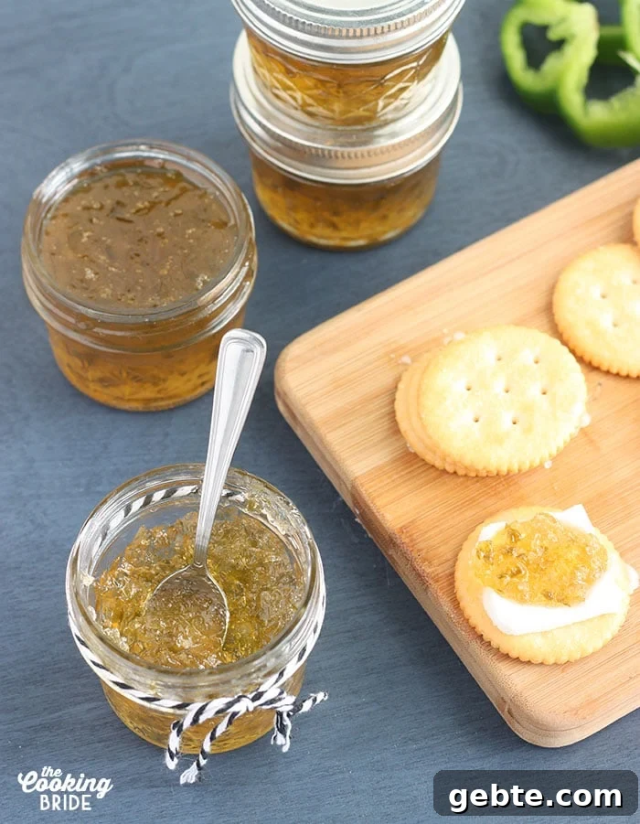 small jelly jar of pepper jelly with crackers, fresh pepper slices and jelly jars in the background