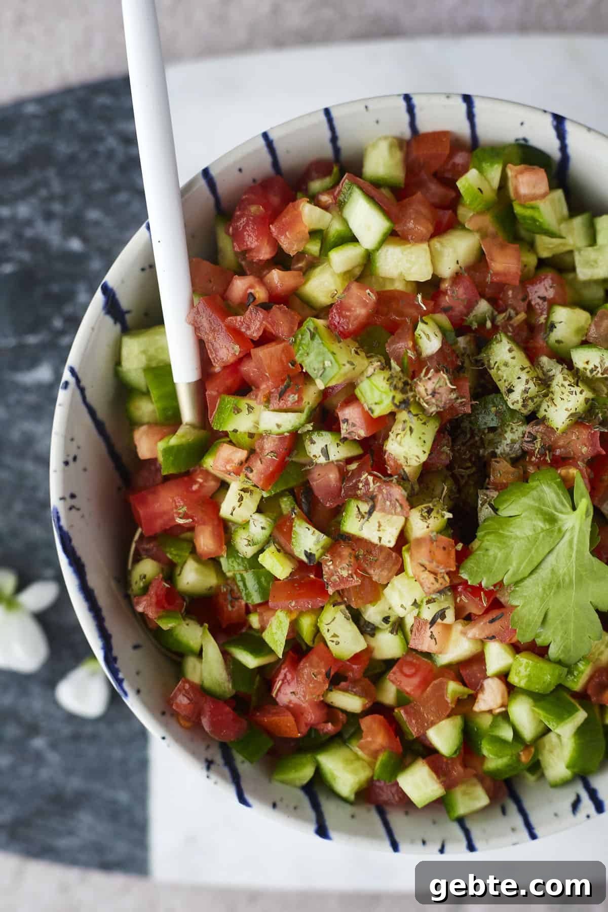 cucumber and tomato salad being stirred with a spoon