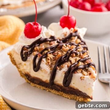 Slice of banana split pie topped with whipped cream, chopped pecans, chocolate syrup, and cherries.