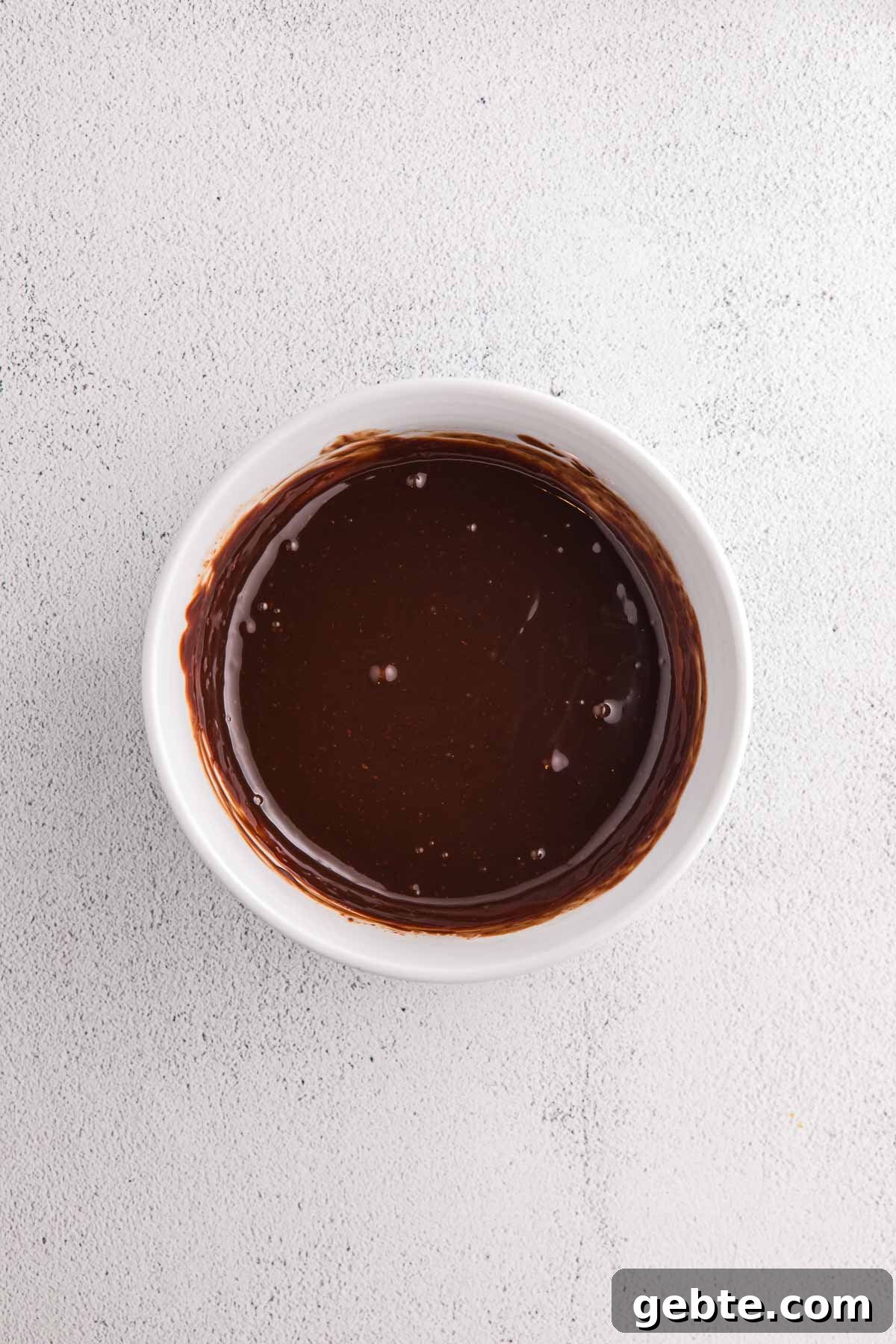 Bowl of melted chocolate prepared for no bake banana split pie.