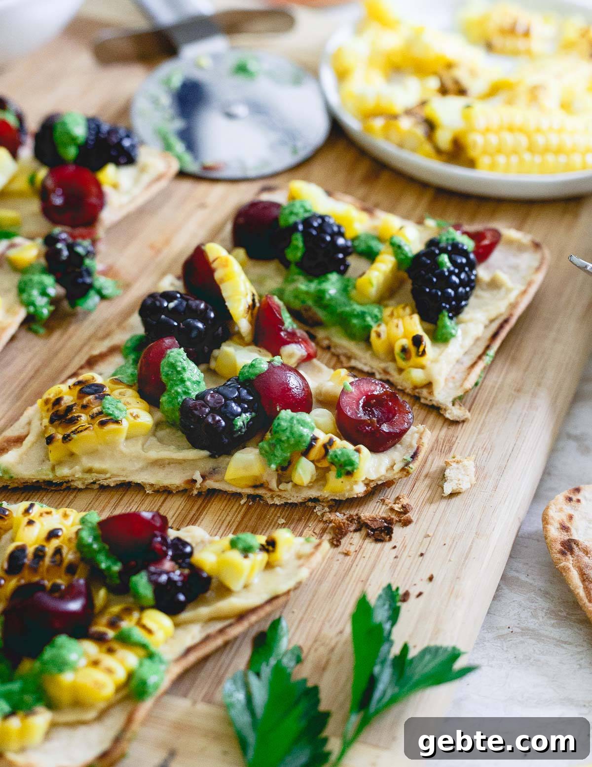 This summer inspired hummus flatbread is topped with grilled corn, berries and drizzled with a fresh roasted garlic parsley pesto. A great pre-dinner bite! This summer inspired hummus flatbread is topped with grilled corn, berries and drizzled with a fresh roasted garlic parsley pesto. A great pre-dinner bite!