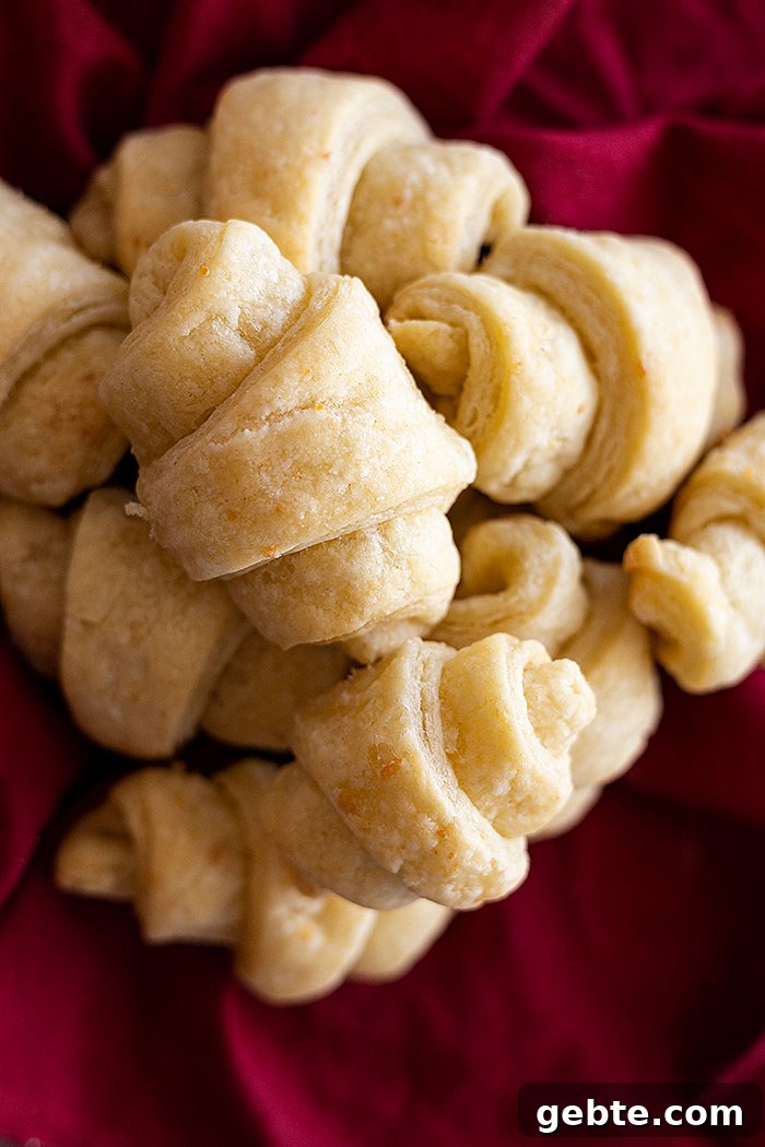 Overhead view of several rolls stacked on top of one another on top of a dark red cloth napkin.