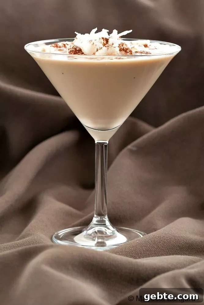 Close-up of the Sweet Dreams Cocktail showing layers of Baileys, Kahlua, and Malibu, topped with whipped cream and coconut shavings.