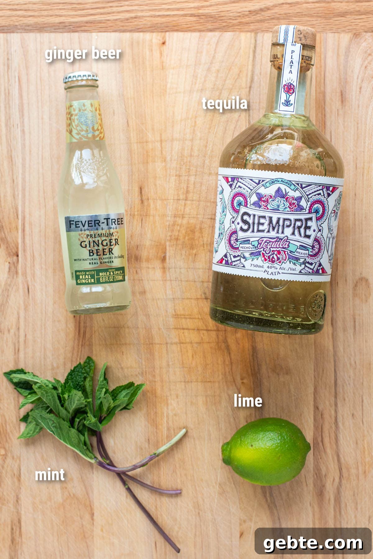 Tequila Mule cocktail ingredients laid out on a wooden cutting board.