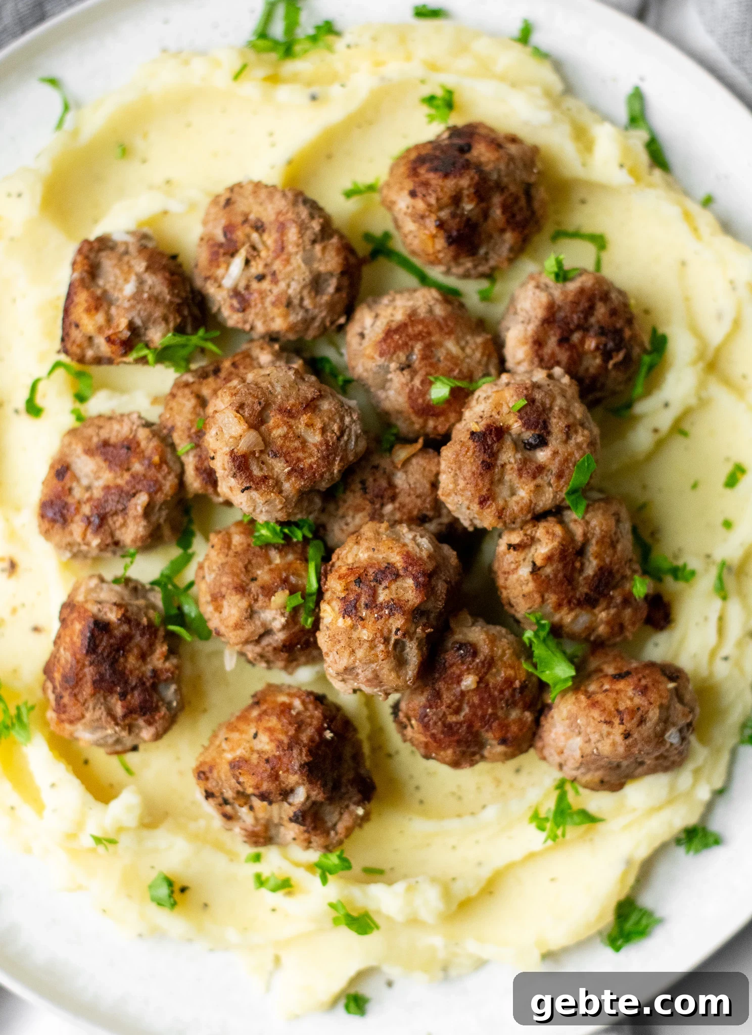 Authentic Swedish Köttbullar Recipe: Classic Meatballs with Creamy Gravy 2 Swedish meatballs and mashed potatoes on a plate.