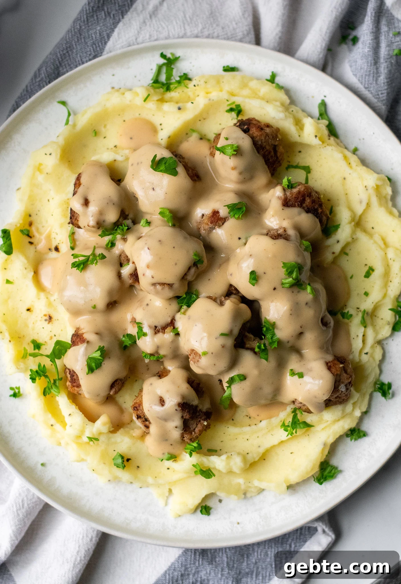 Authentic Swedish Köttbullar Recipe: Classic Meatballs with Creamy Gravy 3 Swedish meatballs with gravy and mashed potatoes on a plate.