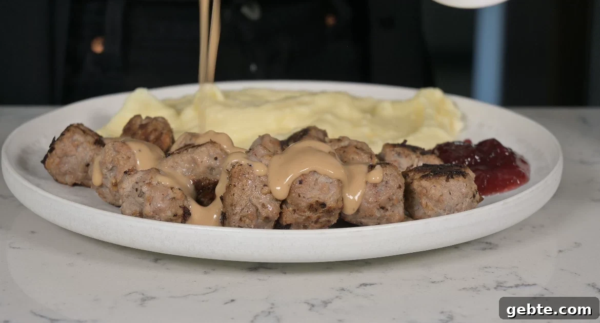 Authentic Swedish Köttbullar Recipe: Classic Meatballs with Creamy Gravy 23 Plate of meatballs with gravy, mashed potatoes, and lingonberry jam.