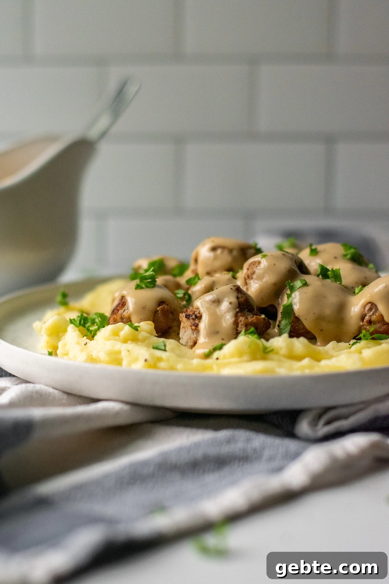 Authentic Swedish Köttbullar Recipe: Classic Meatballs with Creamy Gravy 4 Swedish meatballs with gravy and mashed potatoes on a plate.