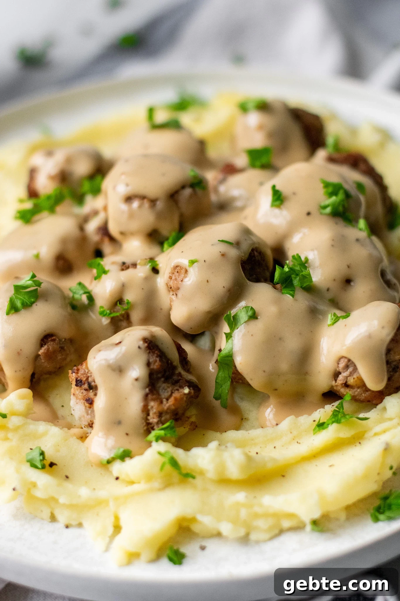 Authentic Swedish Köttbullar Recipe: Classic Meatballs with Creamy Gravy 5 Swedish meatballs with gravy and mashed potatoes on a plate.