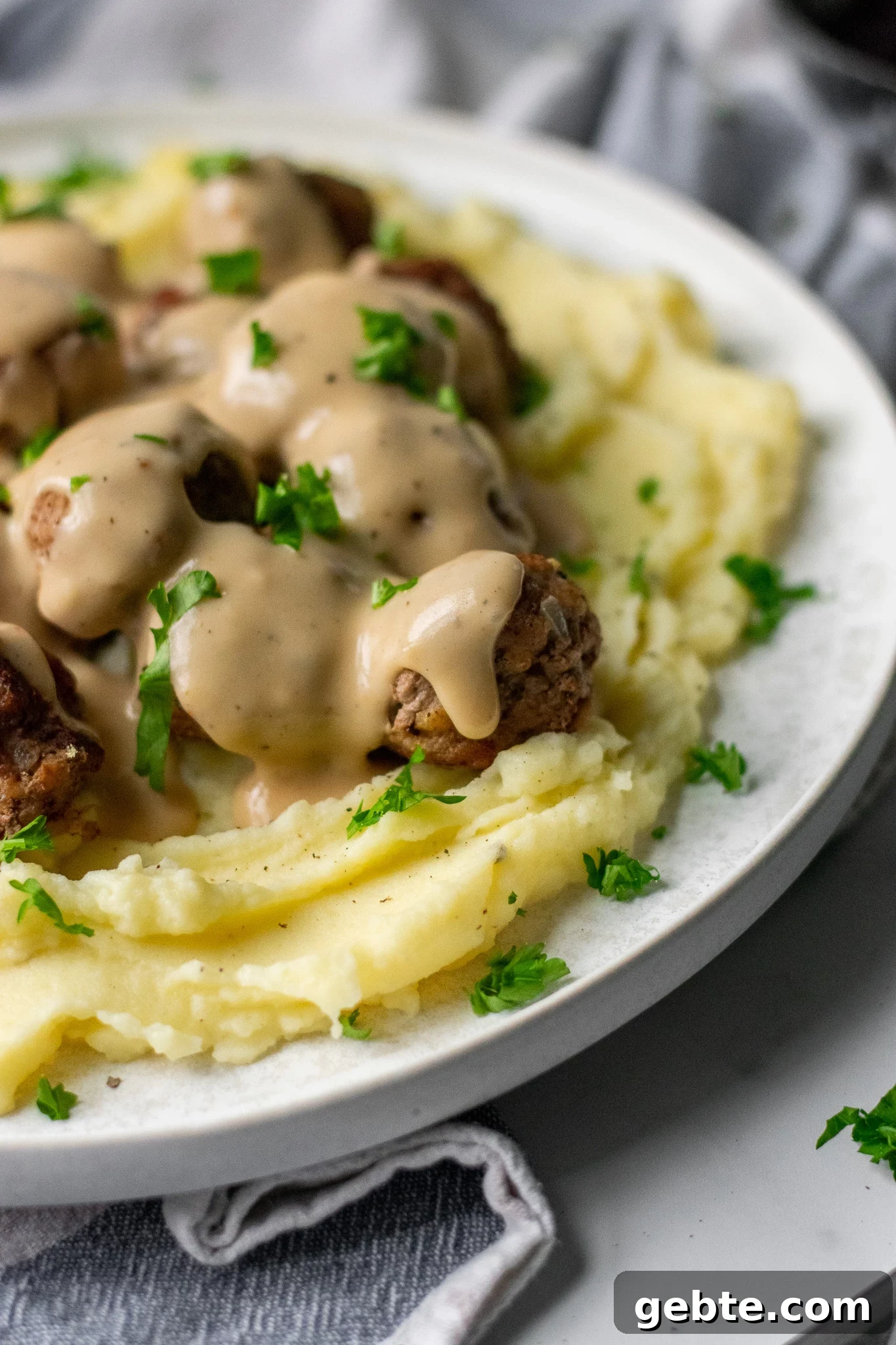 Authentic Swedish Köttbullar Recipe: Classic Meatballs with Creamy Gravy 7 Swedish meatballs with gravy and mashed potatoes on a plate.