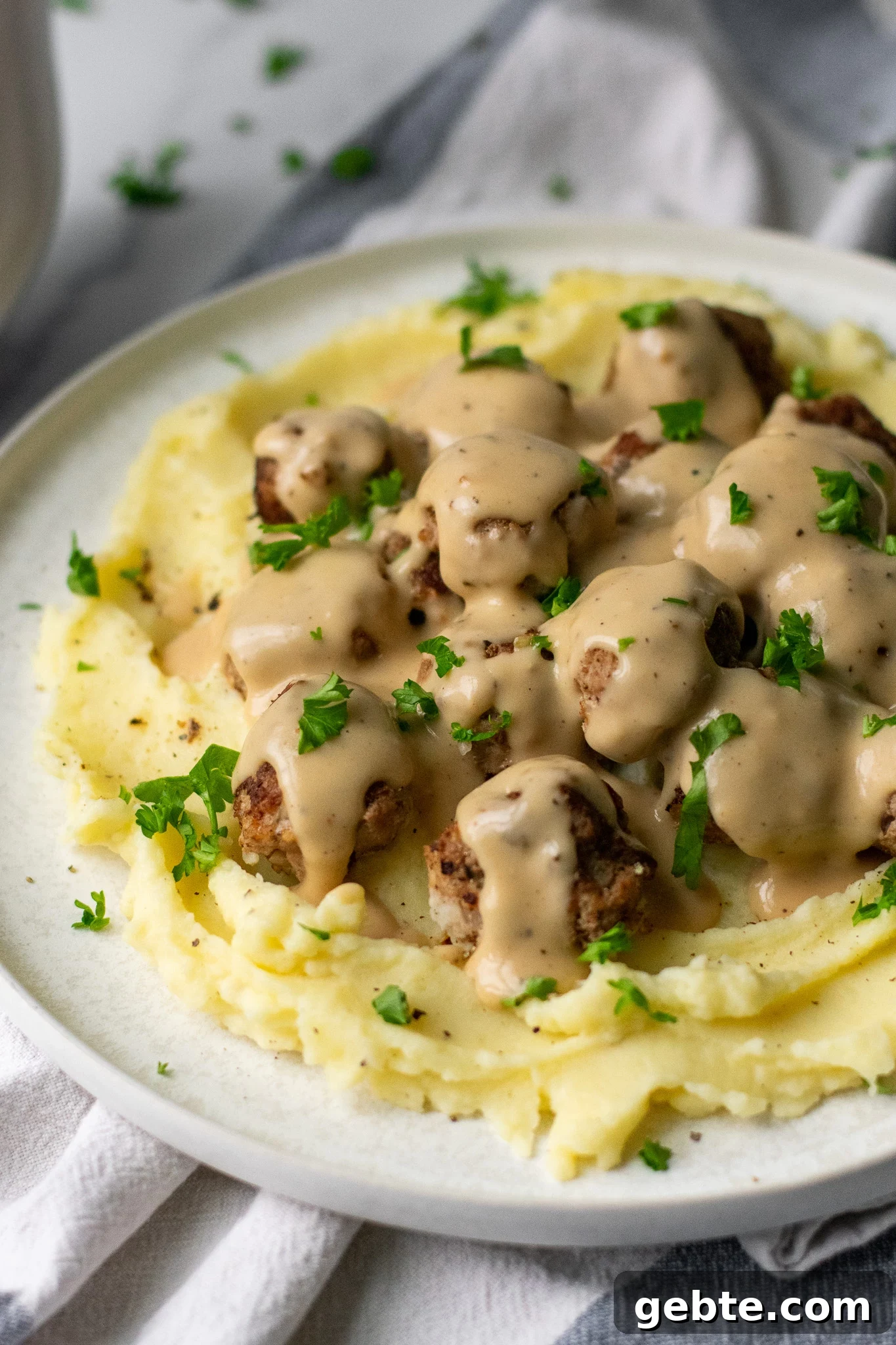 Authentic Swedish Köttbullar Recipe: Classic Meatballs with Creamy Gravy 9 Swedish meatballs with gravy and mashed potatoes on a plate.