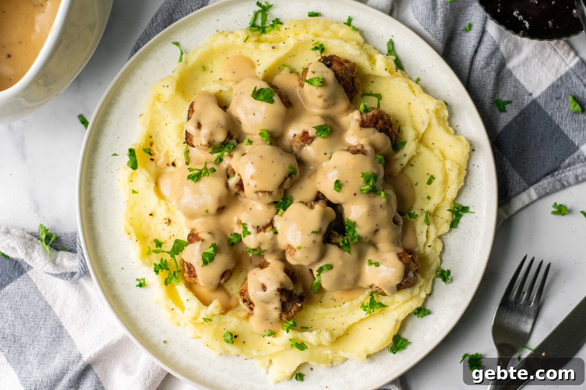 Authentic Swedish Köttbullar Recipe: Classic Meatballs with Creamy Gravy 10 Swedish meatballs with gravy and mashed potatoes on a plate.