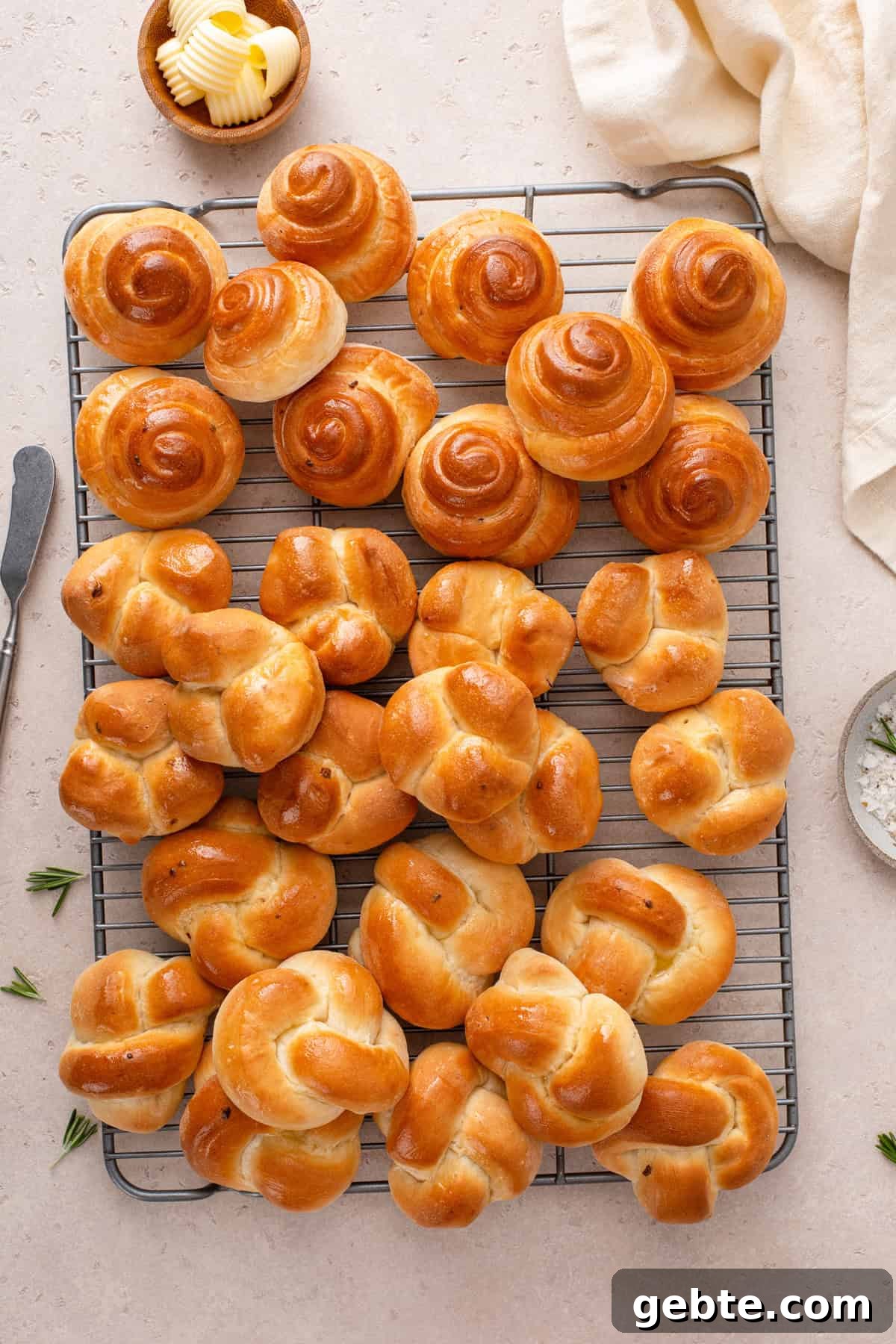 Three shapes of brown and serve dinner rolls arranged on a wire rack.