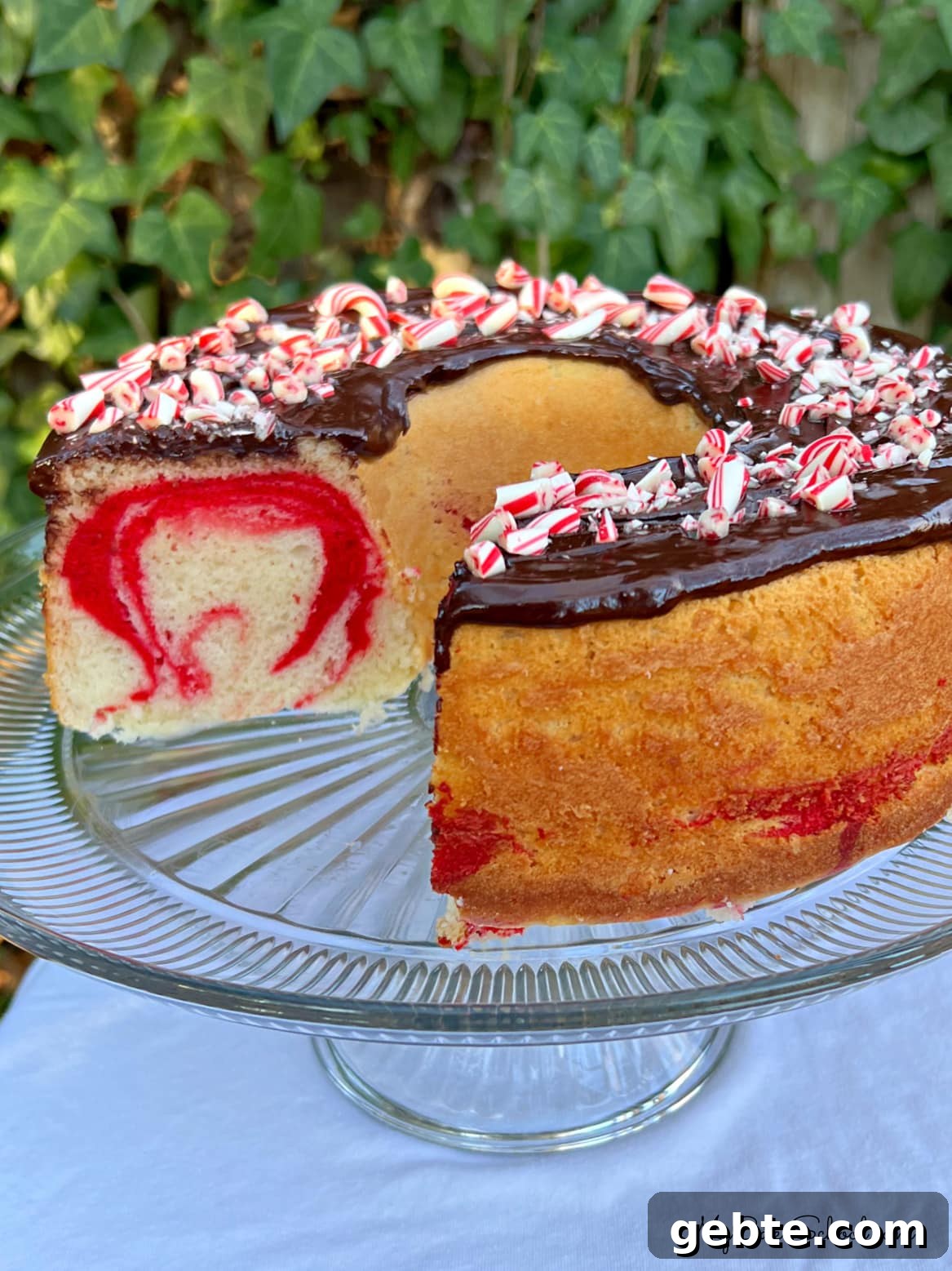 Sliced Peppermint Bundt Cake on a pedestal with chocolate glaze.