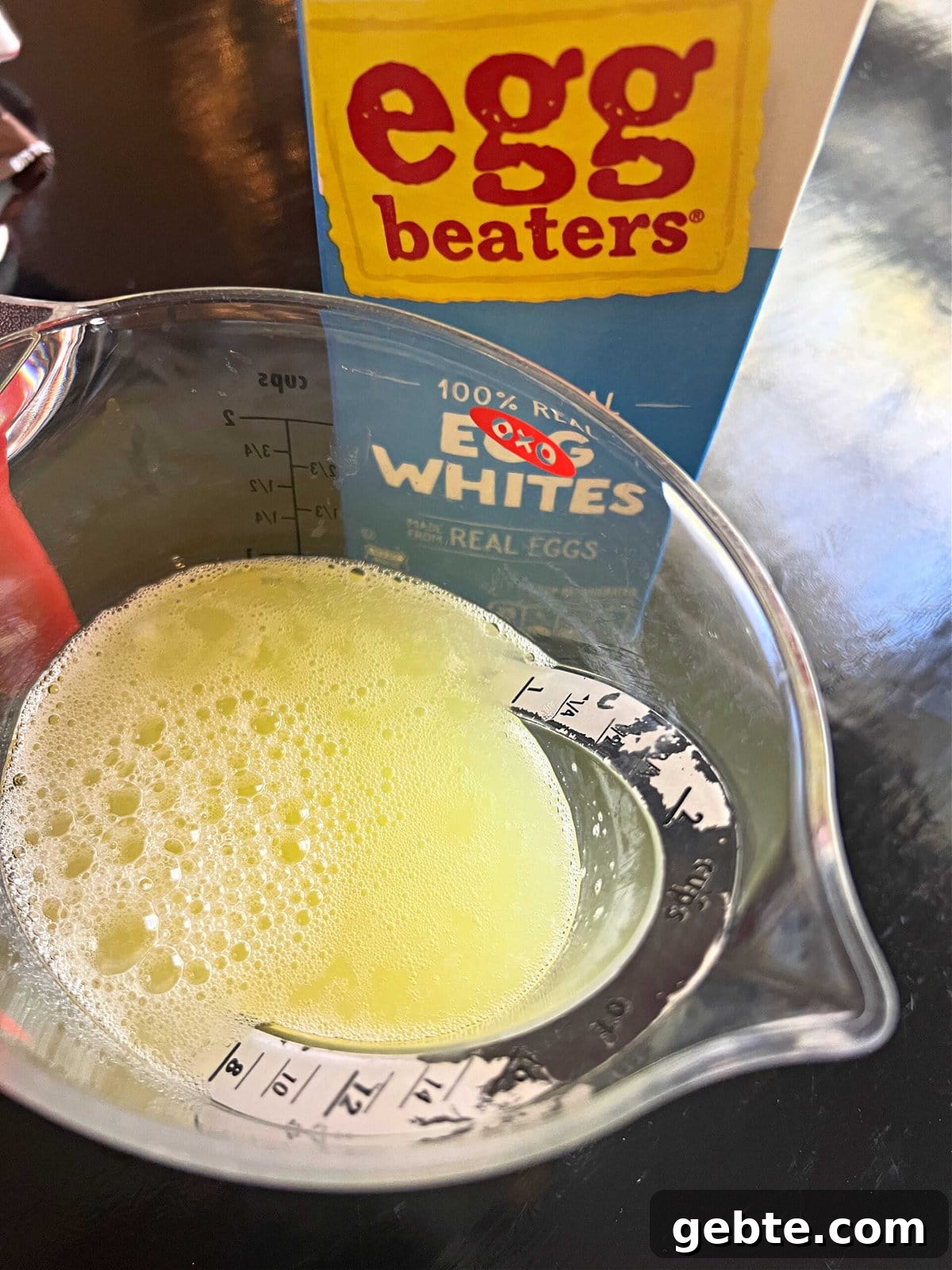 Carton Egg whites poured into a measuring cup.