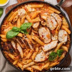 Creamy Vodka Penne with Grilled Chicken and Parmesan 13 A skillet with vodka penne and sliced chicken.