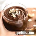 Up close shot of hand holding a glass of chocolate pudding.