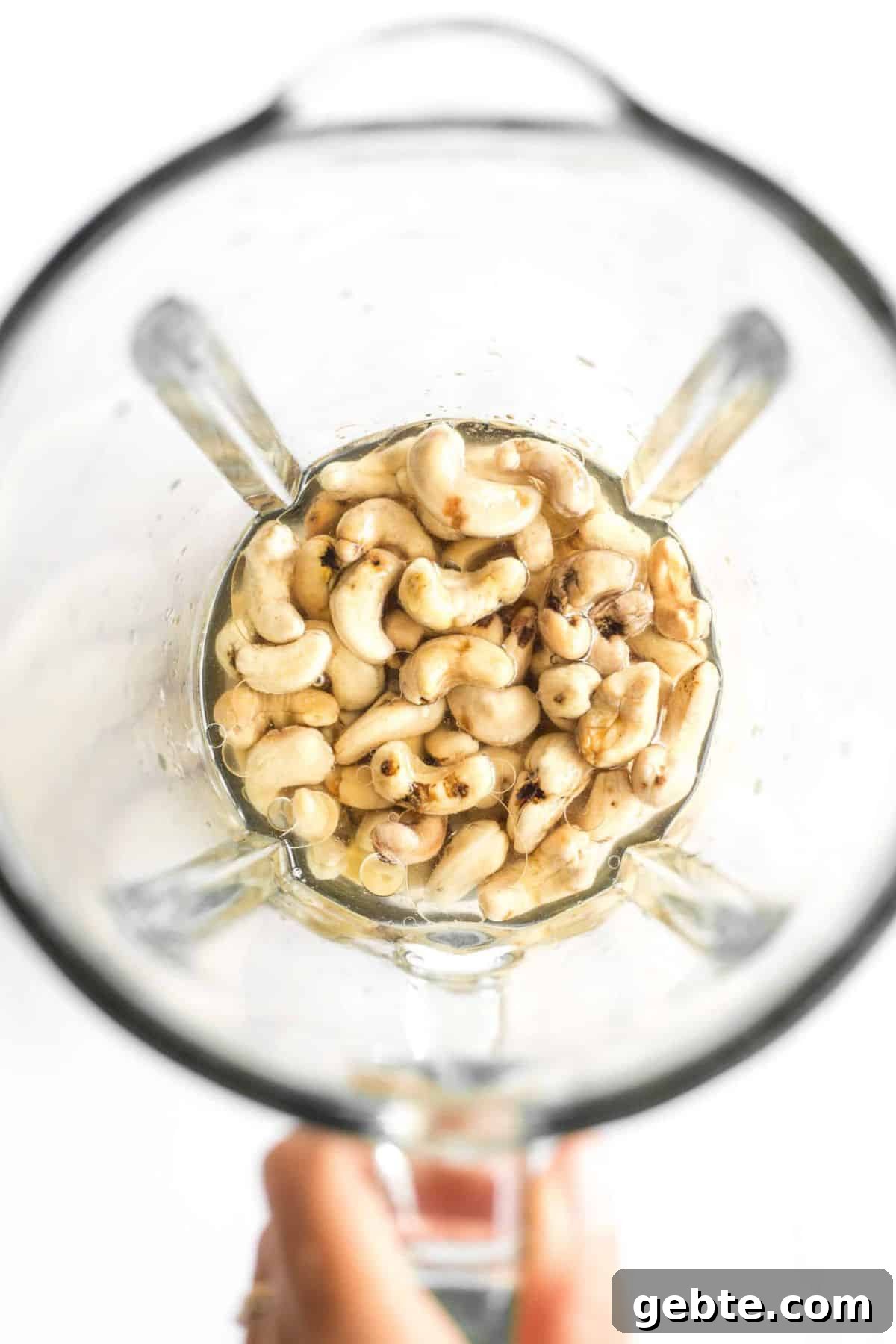 5-Minute Vegan Chocolate Pudding (Gluten-Free, Dairy-Free) Holding a high speed blender with raw cashews and coconut oil.