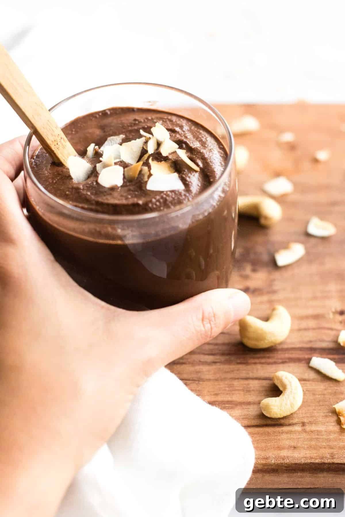 Dairy-free chocolate pudding (gluten-free) Holding a cup of chocolate cashew pudding.