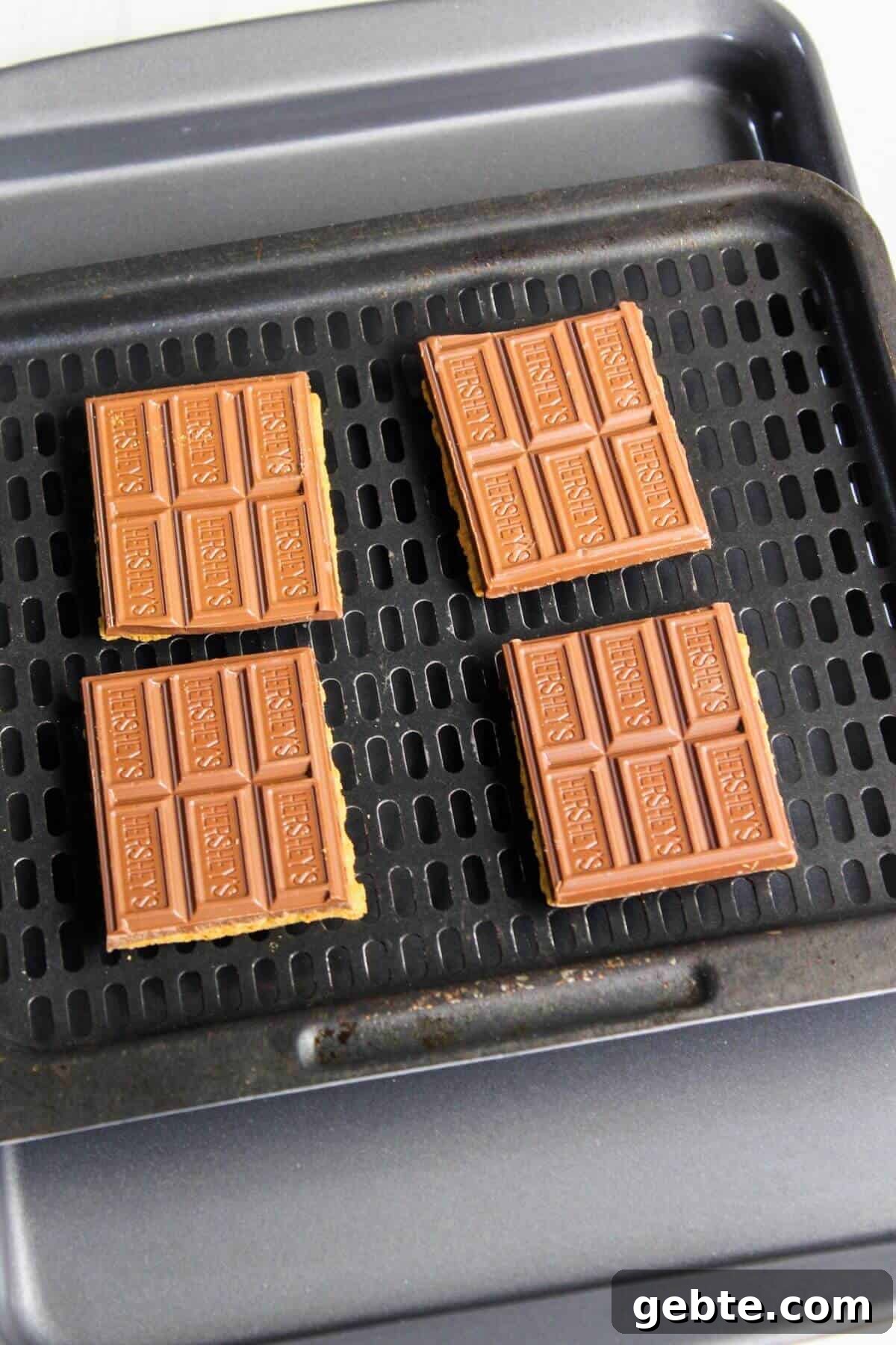 Crispy Air Fryer S'mores Recipe: Gooey Campfire Treats Fast 5 Four chocolate bars over graham crackers on air fryer tray.