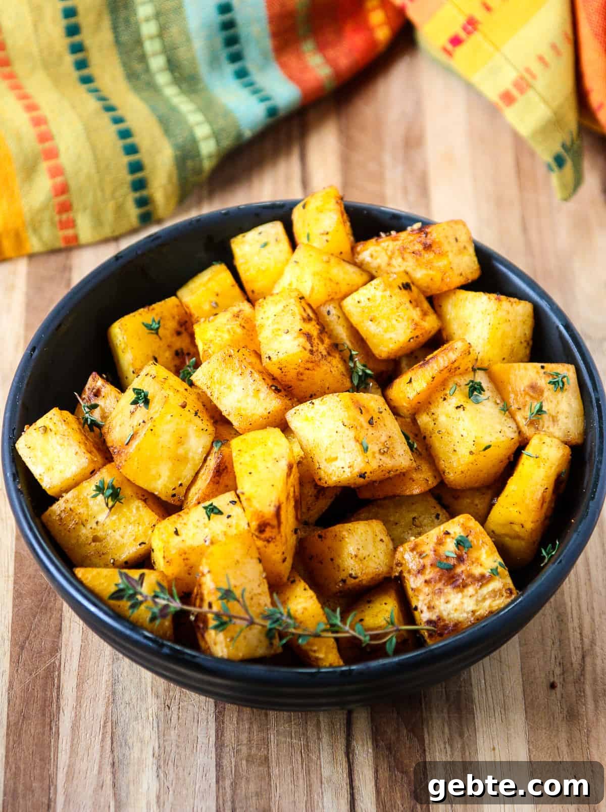 A bowl of the roasted cubes garnished with a sprig of fresh thyme.