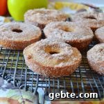 apple cider donuts on a cooling rack with apples in the background