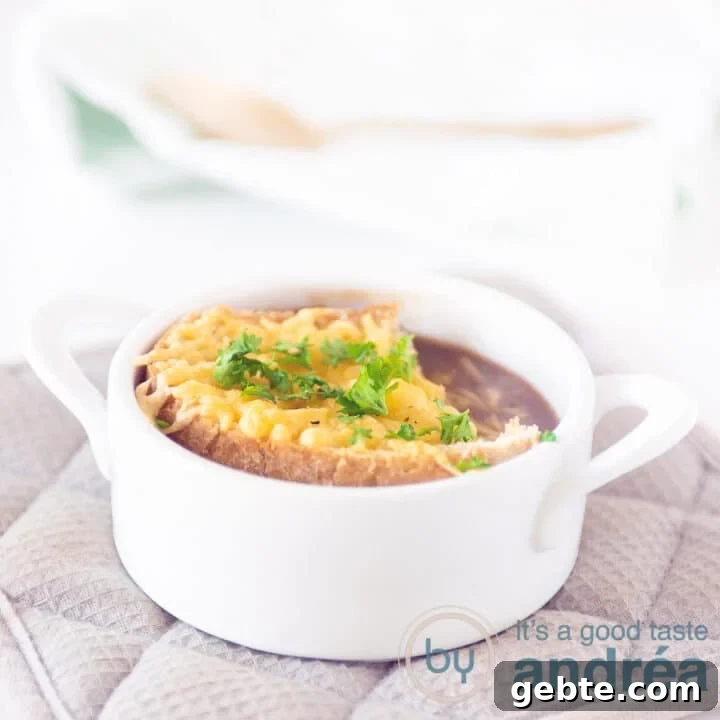 A white soup bowl filled with red onion soup and a piece of gratinated baguette
