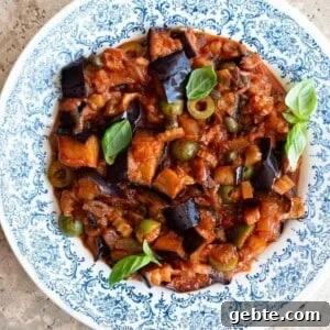 Sicilian Eggplant Caponata Recipe: Authentic Sweet-Sour Relish 12 A close up of Sicilian eggplant caponata in a blue and white bowl with basil on top.