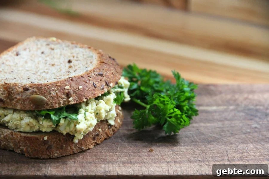 side view of an egg sandwich garnished with a bunch of green parsley
