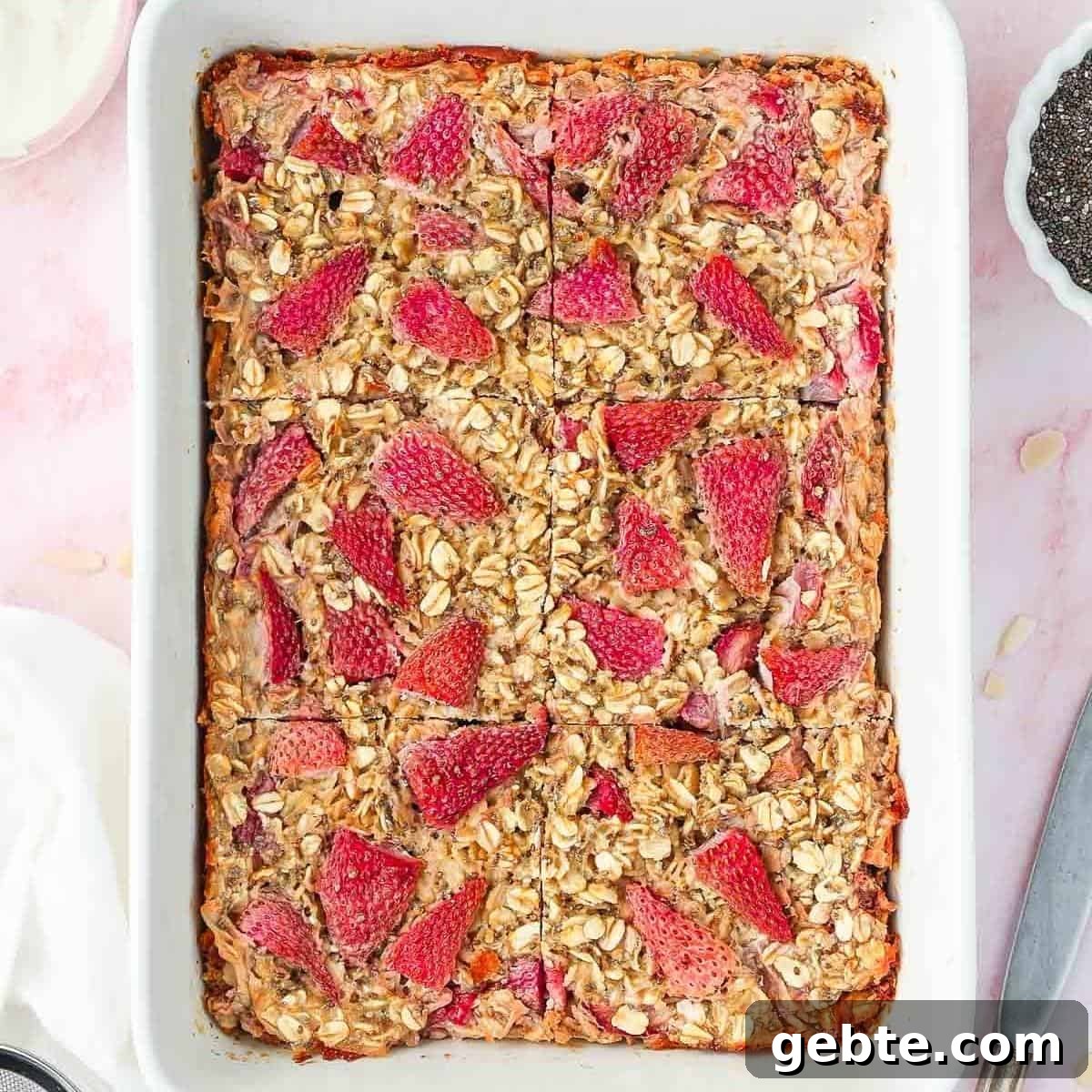 White rectangular dish of baked strawberry oatmeal, cut into six pieces.