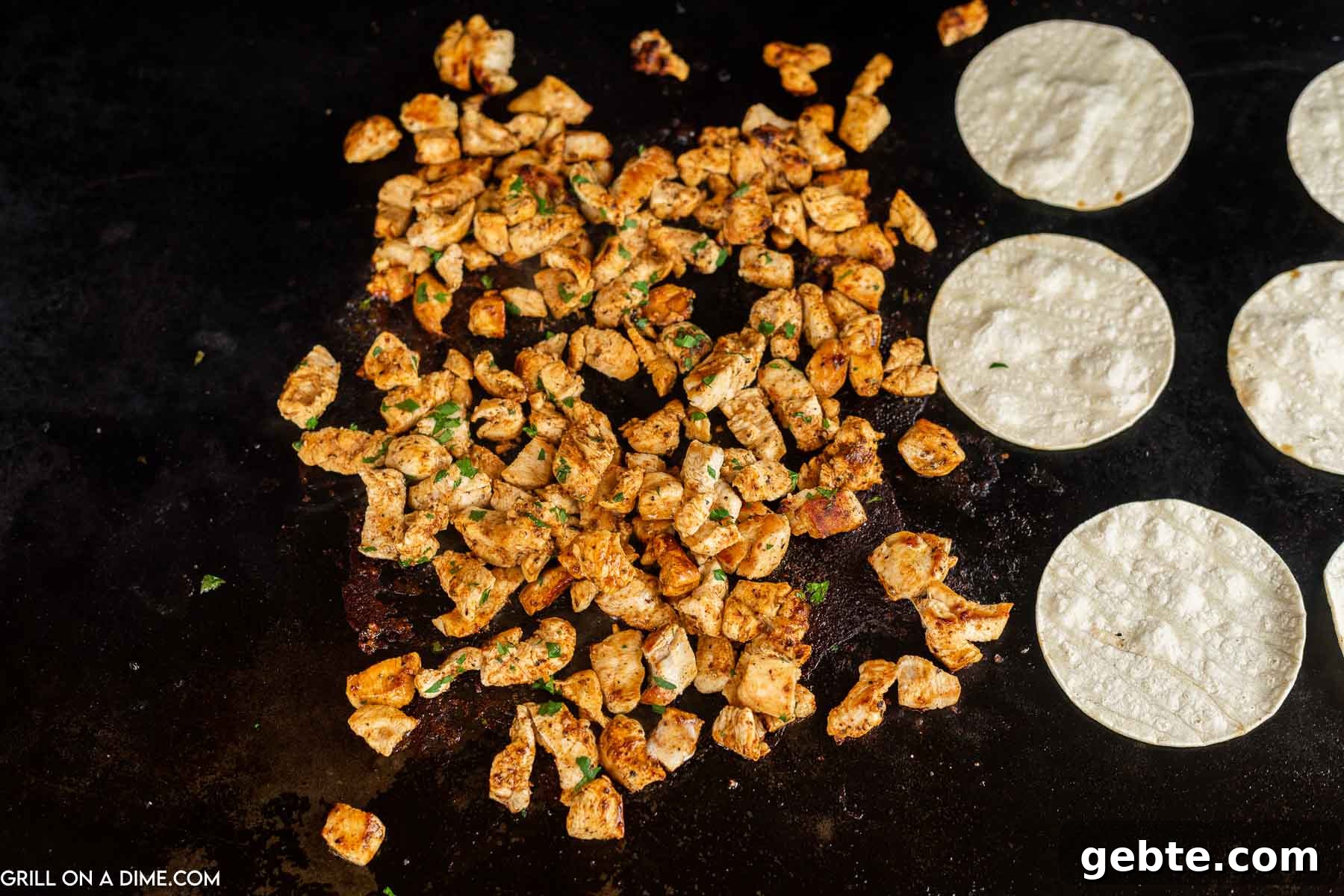 Crispy Blackstone Chicken Tacos with Charred Corn Salsa 5 Cooked chicken bites and tortillas on the griddle.