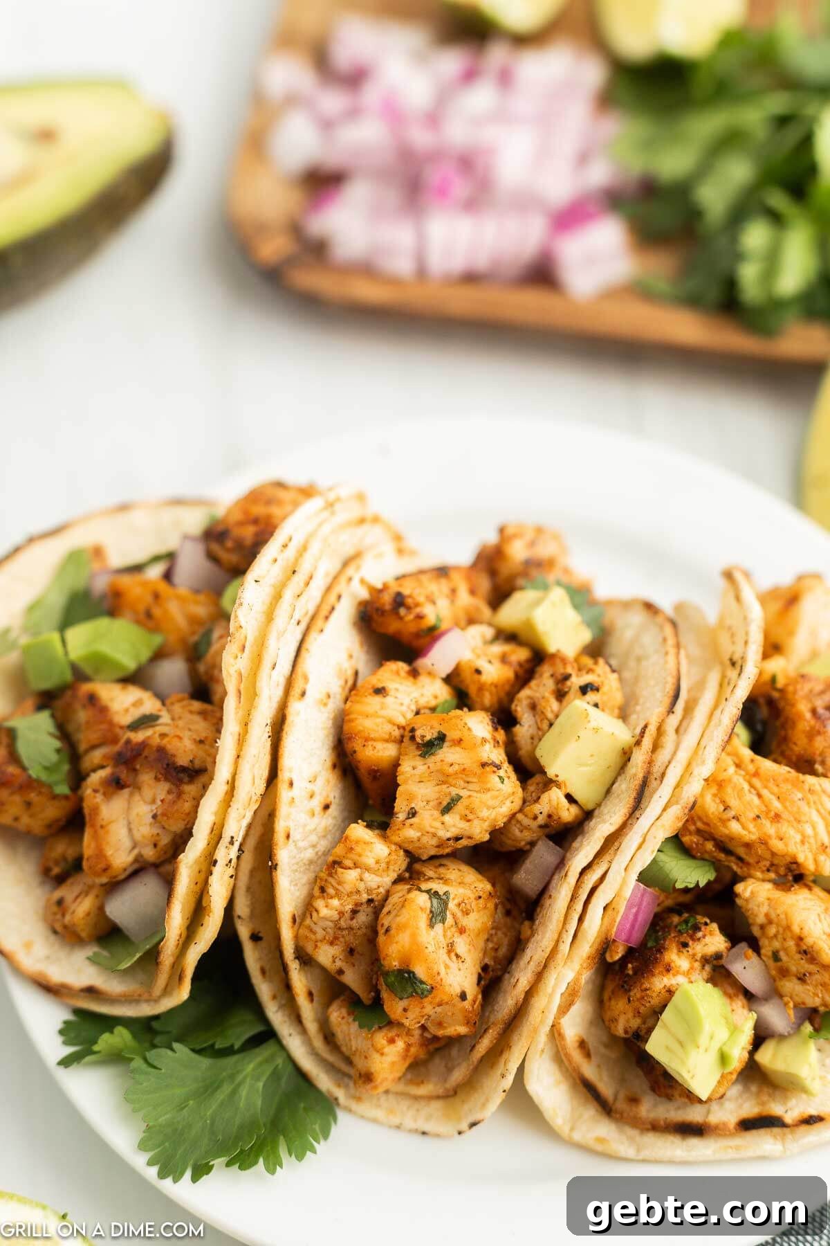 Crispy Blackstone Chicken Tacos with Charred Corn Salsa 7 3 chicken tacos on a plate with diced avocados on top.