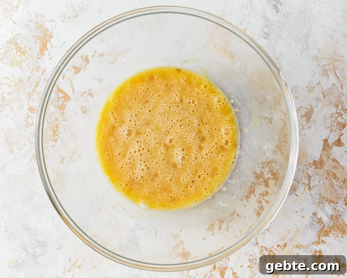 Beaten eggs in a glass mixing bowl.