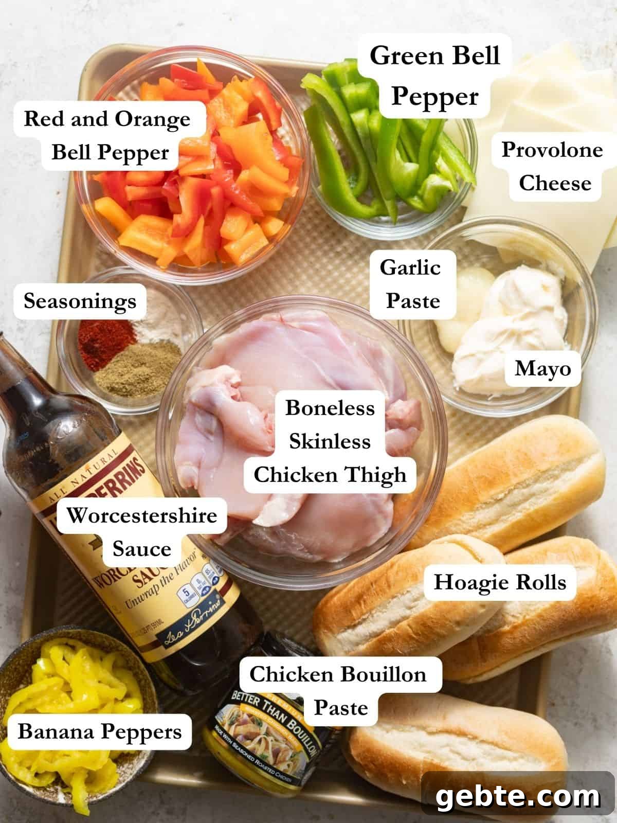 ingredients to make chicken philly sandwich - chicken thighs, bell peppers, onion, worcestershire sauce, banana peppers, hoagie rolls, chicken bouillon paste, garlic, mayo, and seasonings.