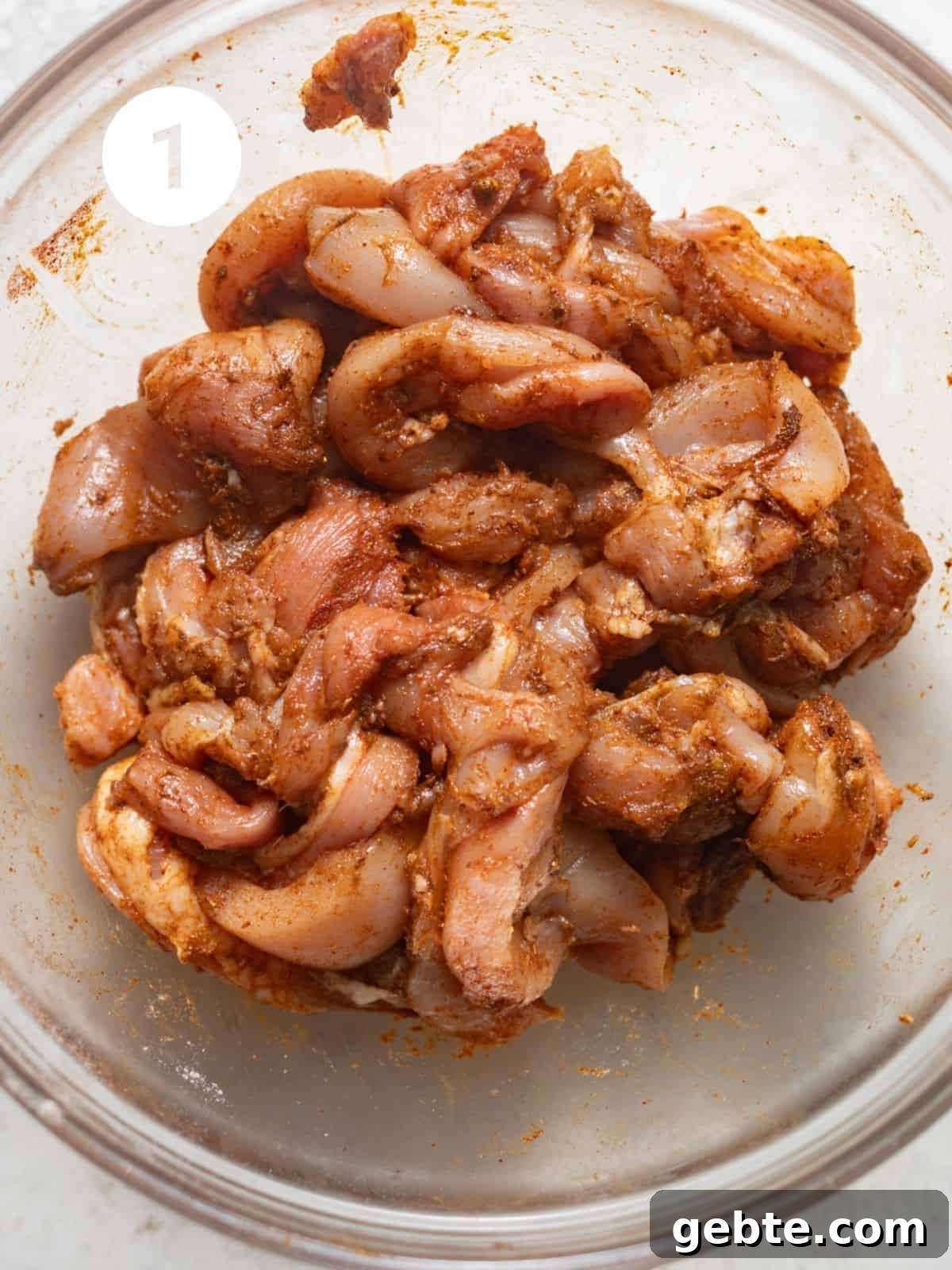 chicken thighs sliced and seasoned in a mixing bowl.