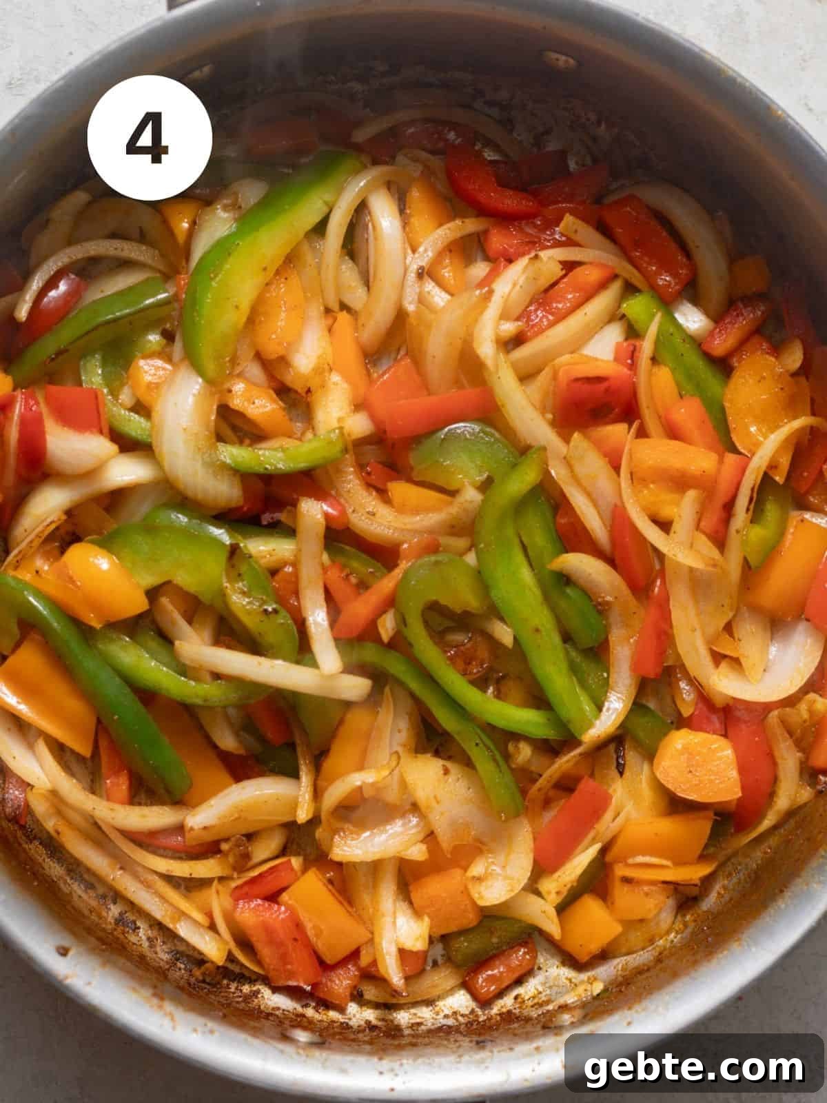 bell peppers and onions sauteed in a pan.