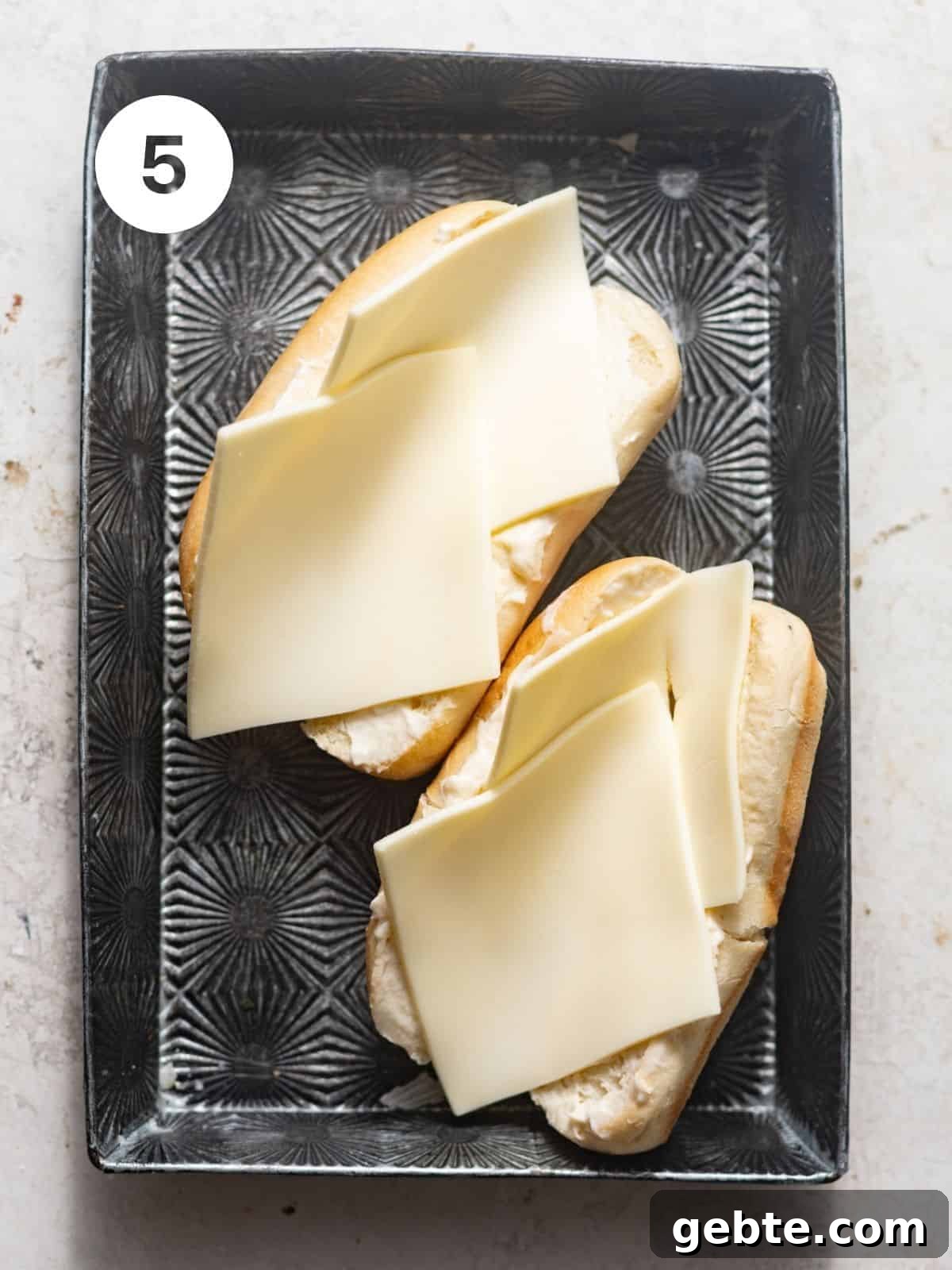 butter toasted hoagie rolls with sliced provolone cheese on top. 